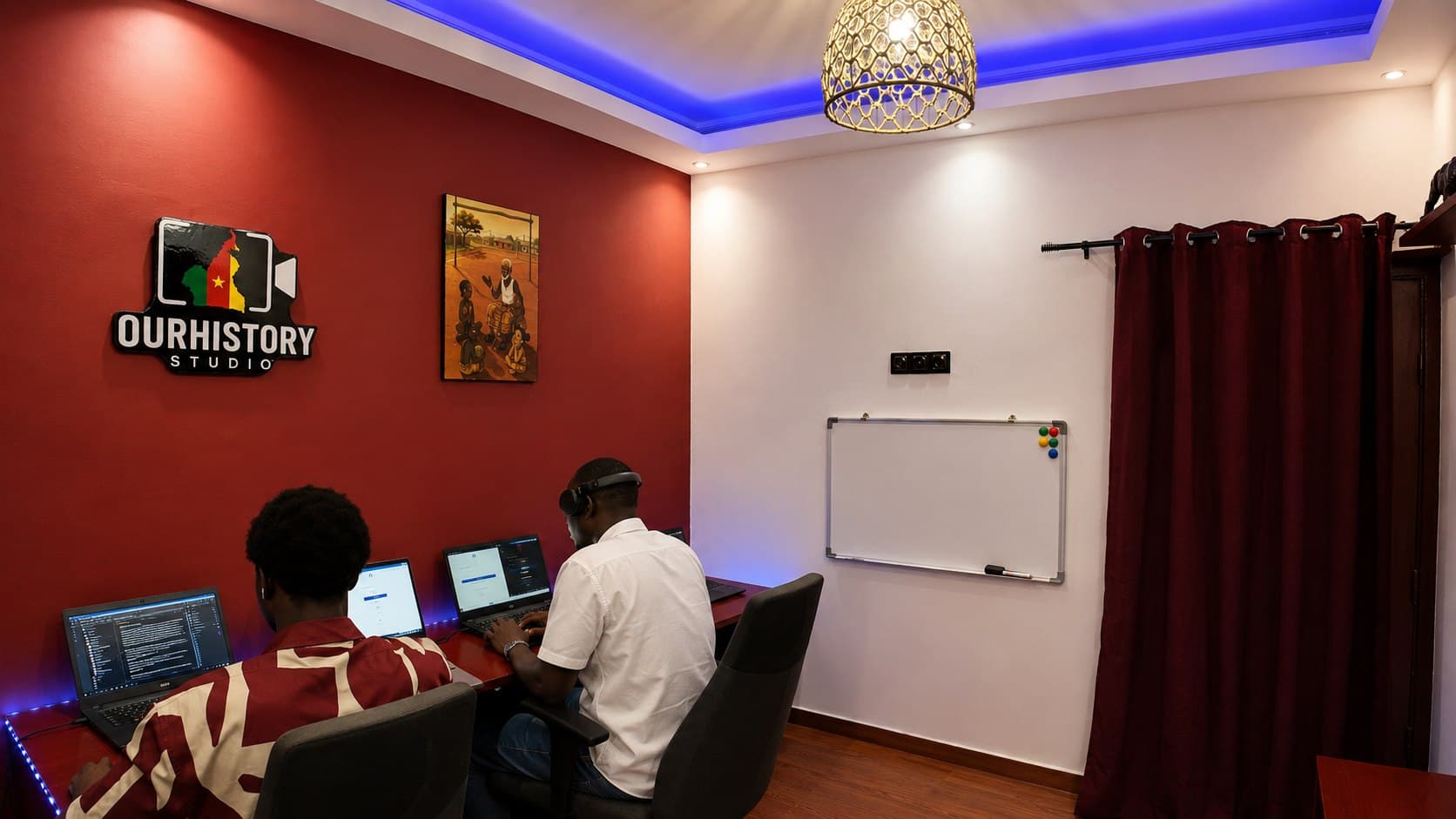 Deux participants travaillent dans l'espace OurHistory Studio, avec le logo du studio visible au mur.